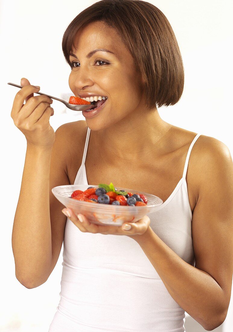 A woman eating a berry salad