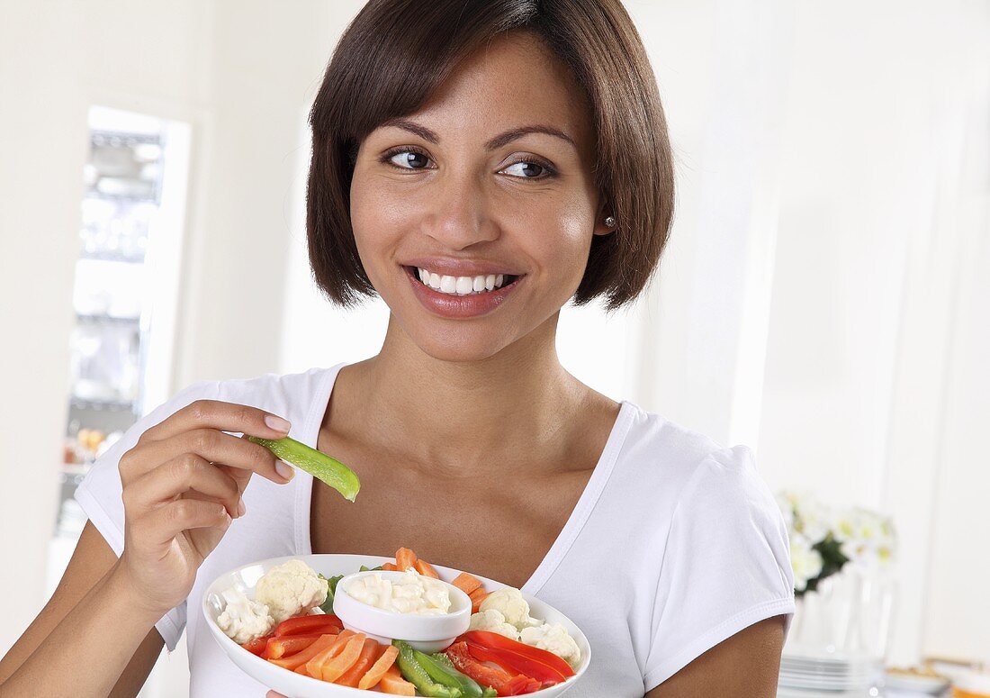 A woman eating crudites with a dip