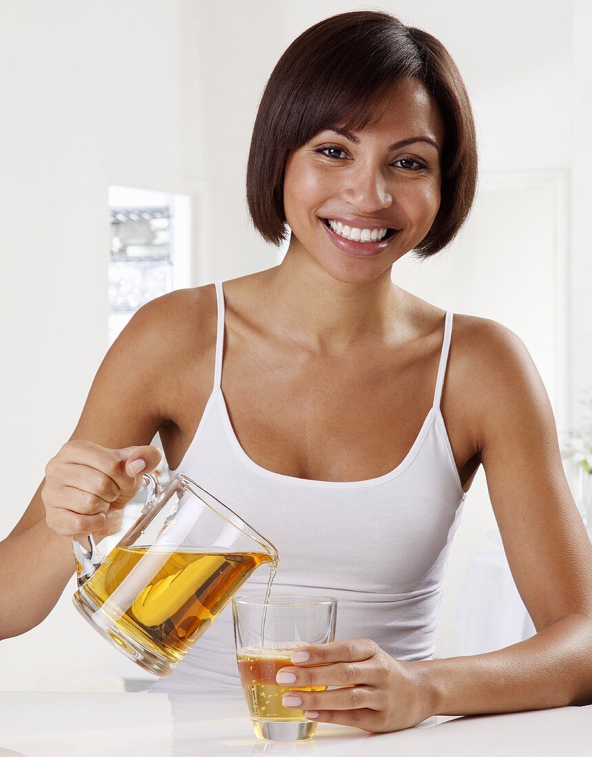 A woman pouring apple juice into a glass