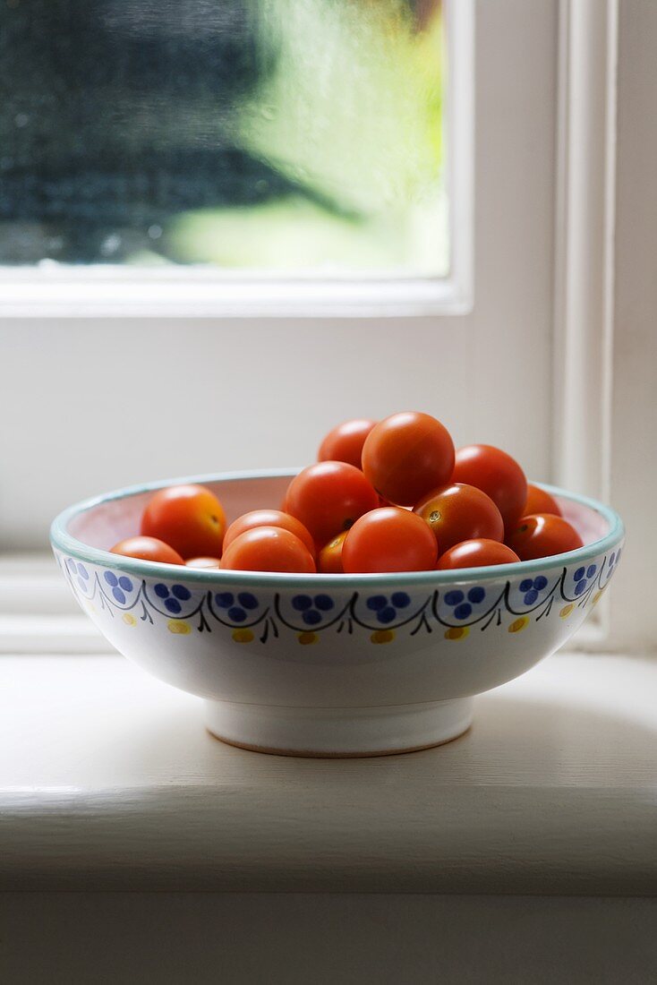 A bowl of cherry tomatoes on a window sill