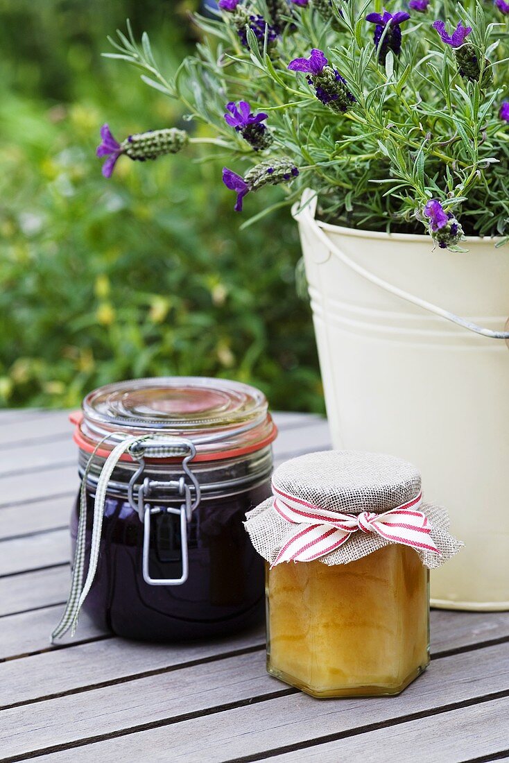 Blackberry jam and a jar of honey on a garden table