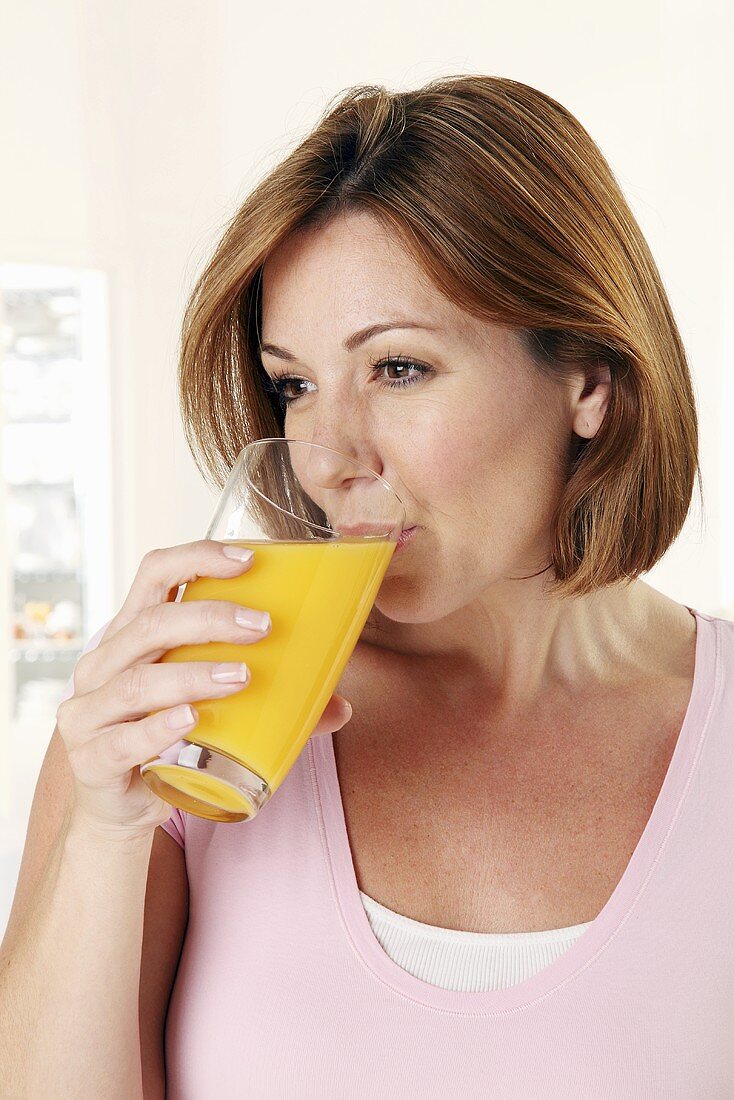 Frau trinkt aus einem Glas mit Orangensaft