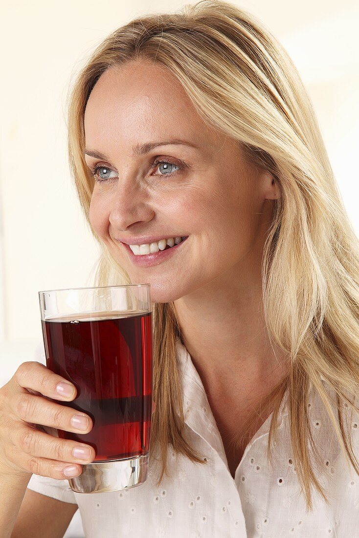 A woman holding a glass of fruit juice