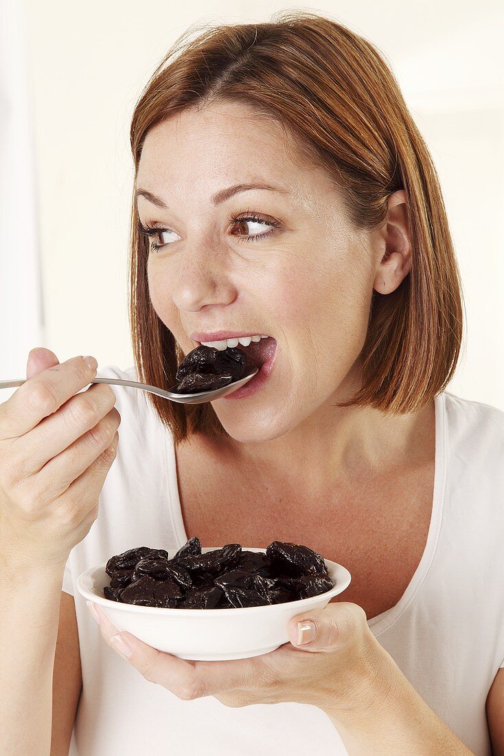 A woman eating dried plums
