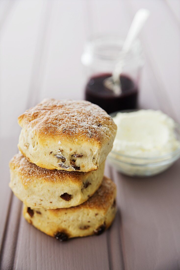 Raisin scones with clotted cream and jam in the background