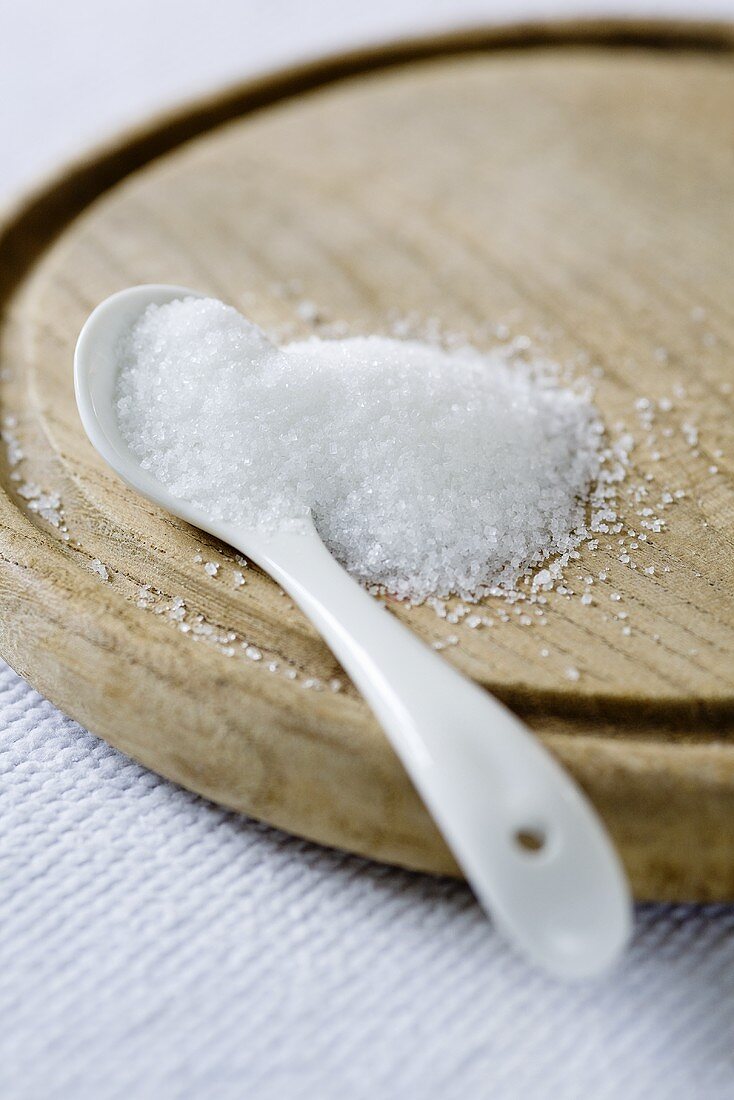 Sugar and a spoon on a wooden board