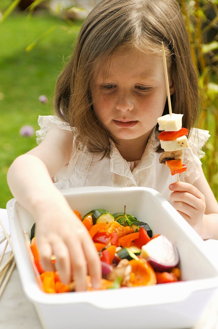 A girl preparing vegetable kebabs for the barbeque