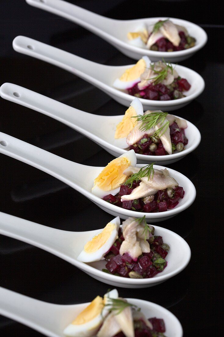 Spoon canapes with hering, egg and beetroot
