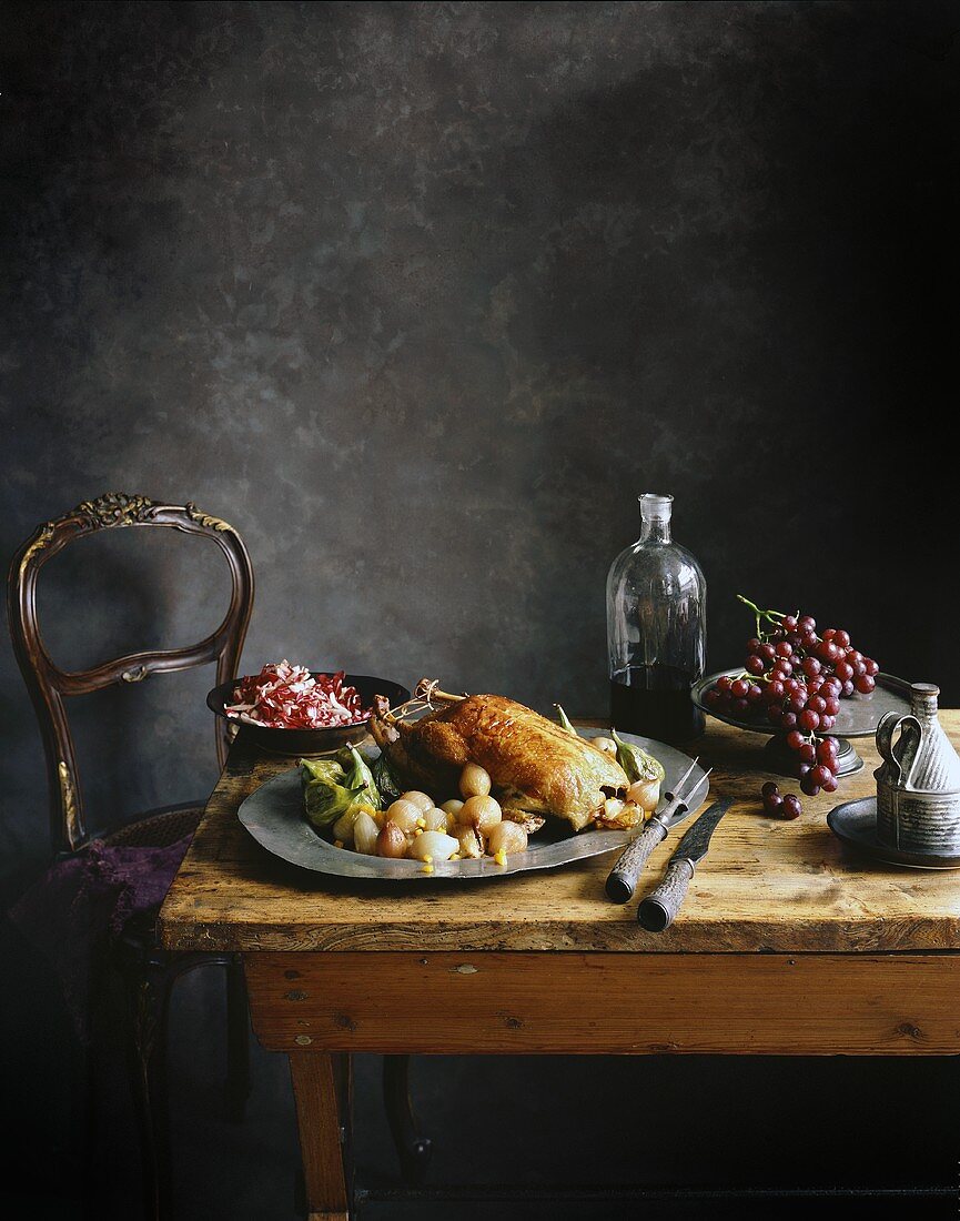 Duck with vegetables and grapes on an old wooden table