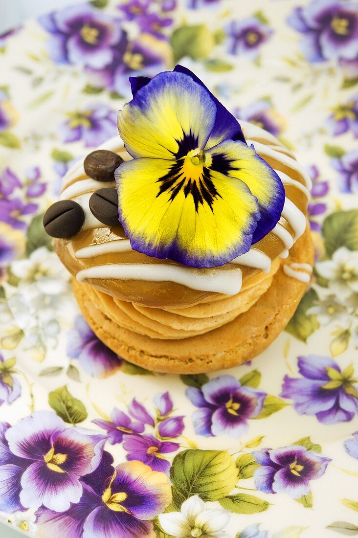 A whoopie pie decorated with a pansy and a coffee bean