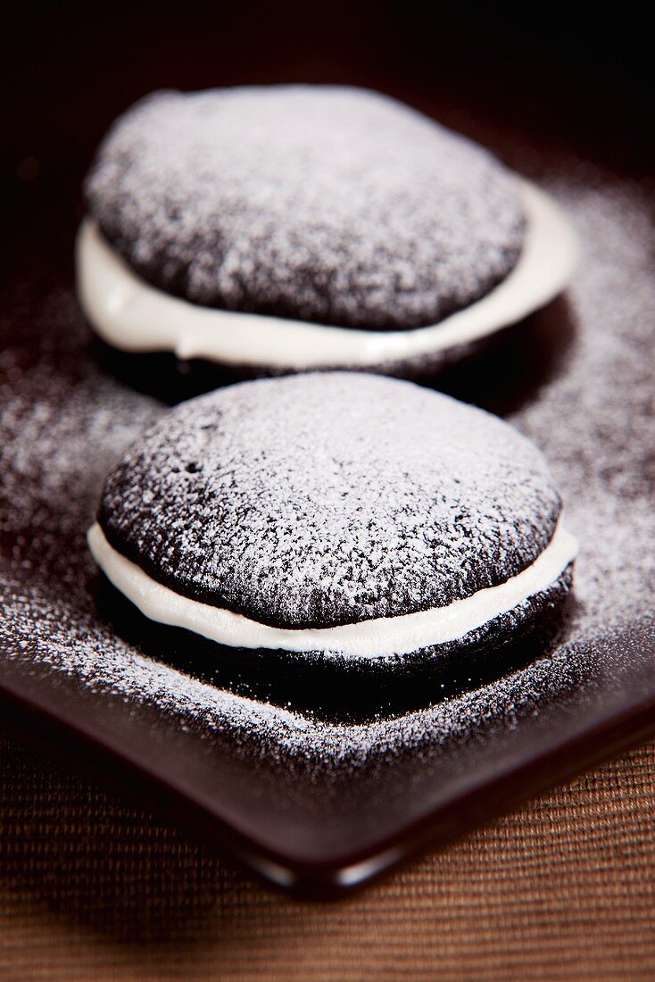 Two chocolate whoopie pies with icing sugar