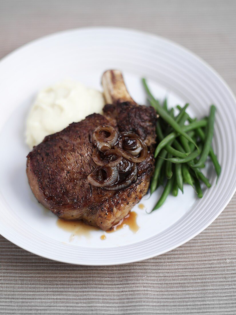 Prime Rib in der Pfanne gebraten mit grünen Bohnen und Kartoffelbrei