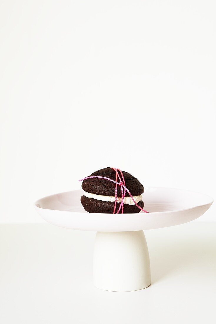 Schokoladen-Whoopie Pie, mit Schnur umwickelt, auf Kuchenständer