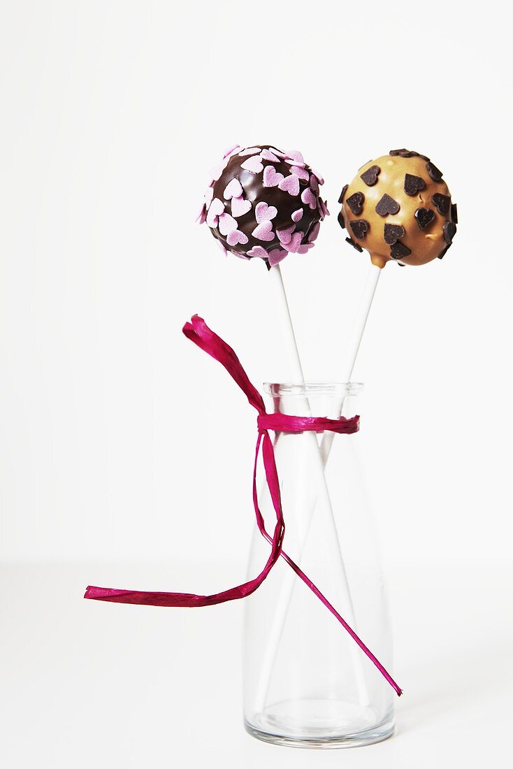 Two lollipops with heart decorations in a vase