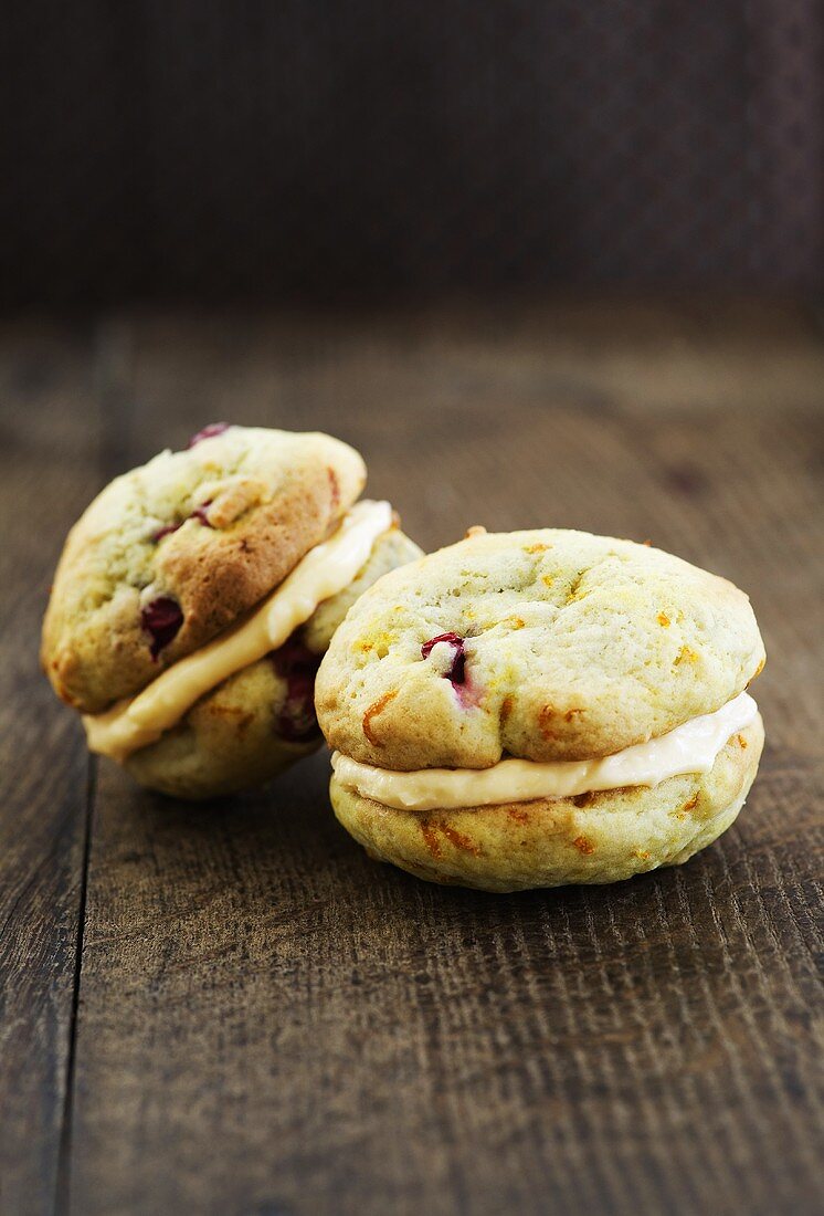 Cranberry-orange Whoopie Pies, filled with orange-vanilla cream on a wooden background