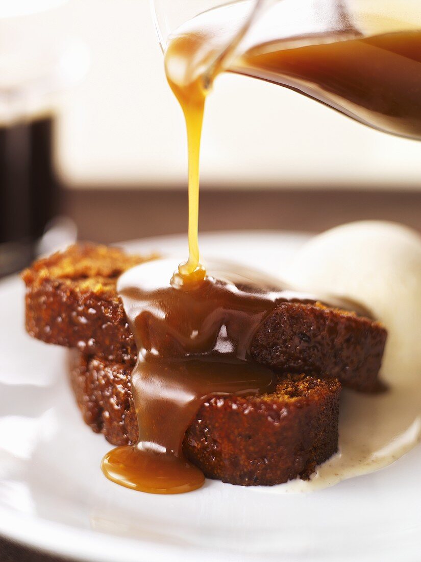 Butterscotch sauce being poured over cake