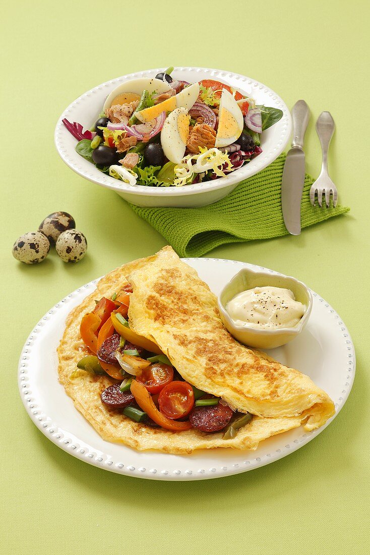 Omelette with chorizo and salad with eggs, olives and tuna