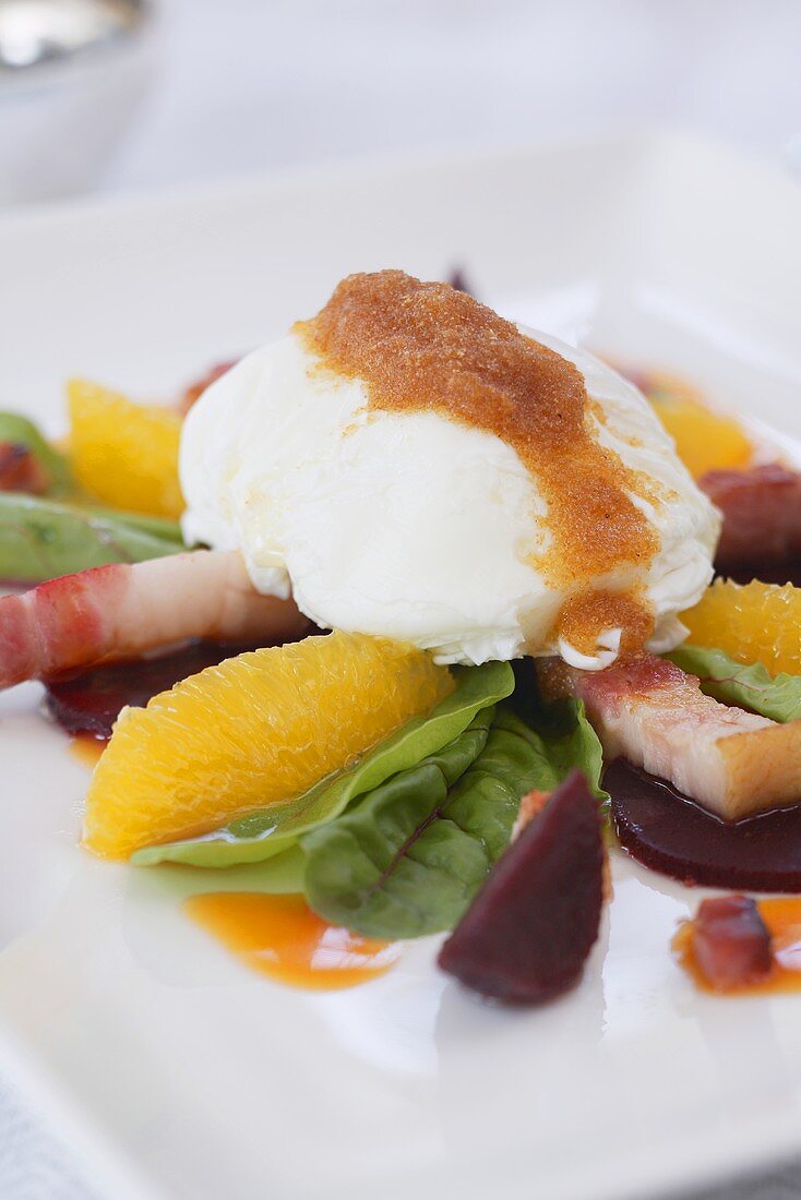 Poached egg on a herb salad with bacon and oranges