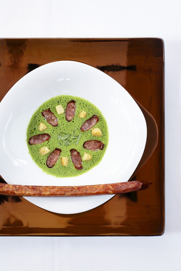 Creamy soup with lamb's lettuce and peppered sausage