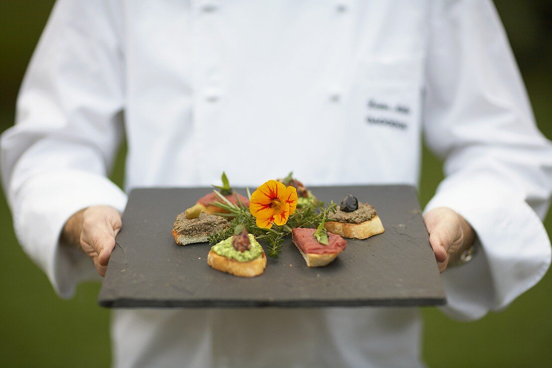 A chef serving a plate of various crostinis
