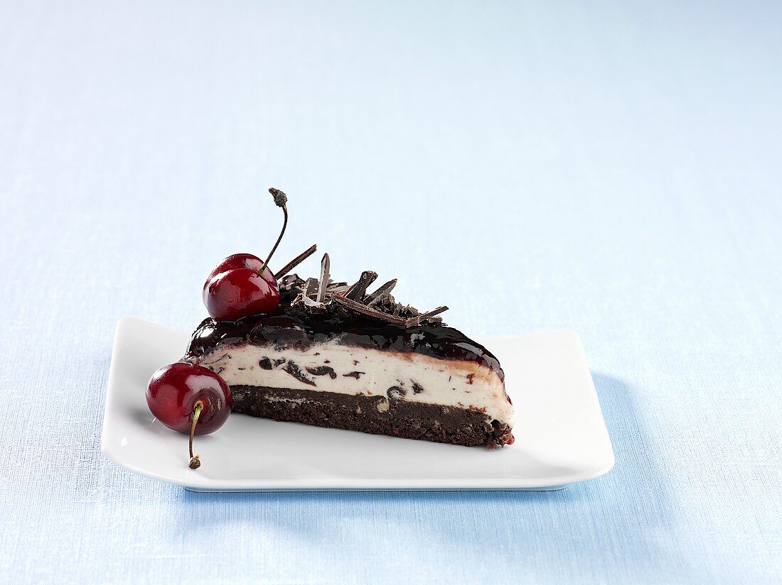 A slice of ice cream cakes with cherries and chocolate