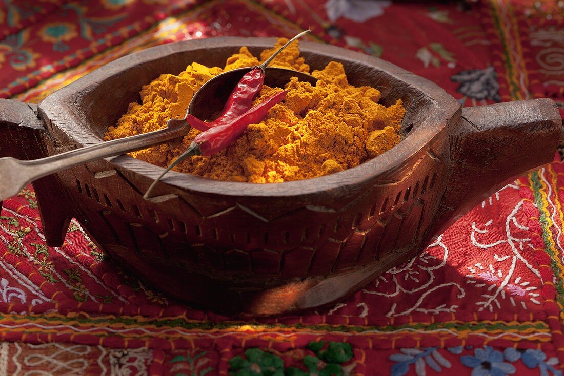 Curry powder and chilli peppers in a wooden bowl