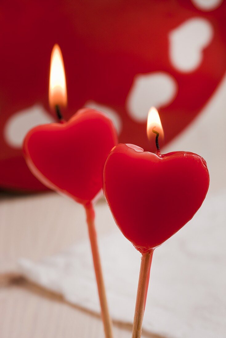 Zwei rote Kerzen in Herzform, brennend