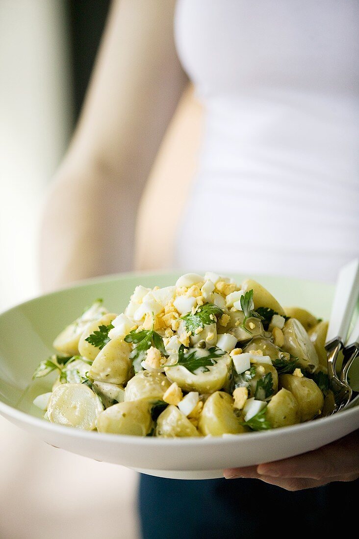 A woman serving potato salad with egg