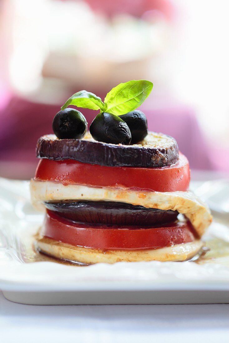 An aubergine, tomato and mozzarella tower with olives