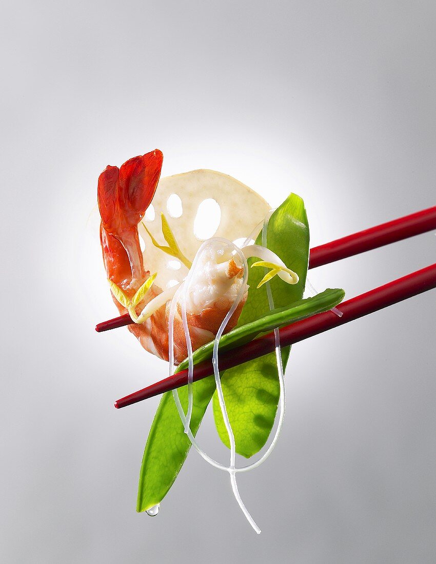 A prawn with mange tout and glass noodle on chopsticks (Asia)