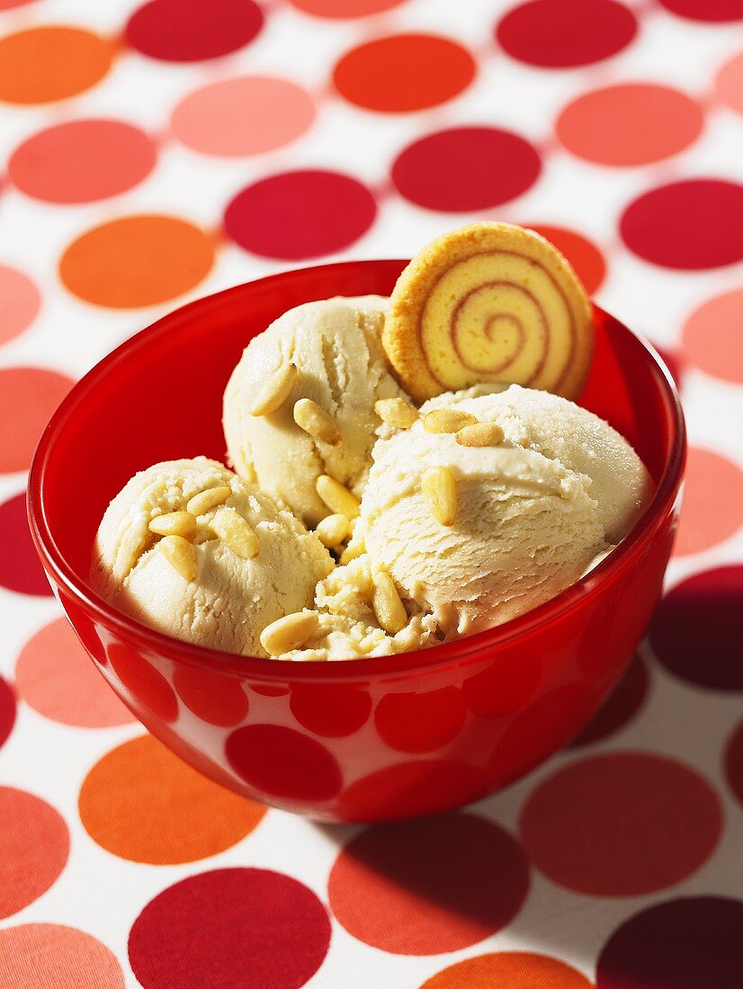 Honey ice cream with pine nuts in a red bowl on a polka dot