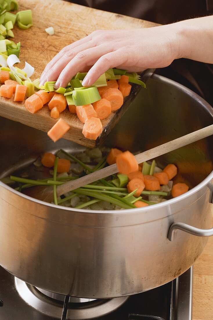 Diced vegetables being added to a pot