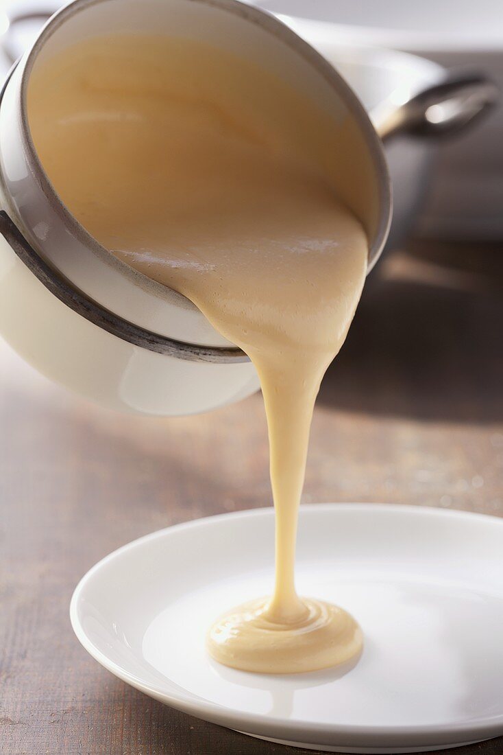 A light sauce being poured onto a plate