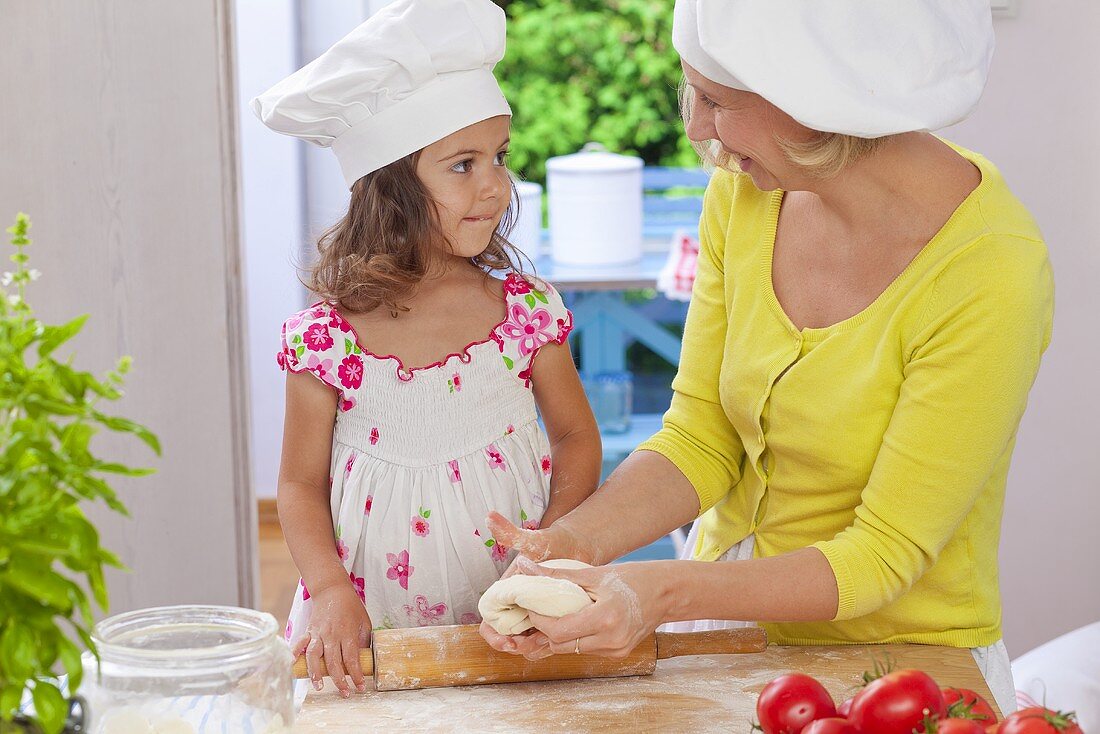 A mother and daughter kneading pizza dough