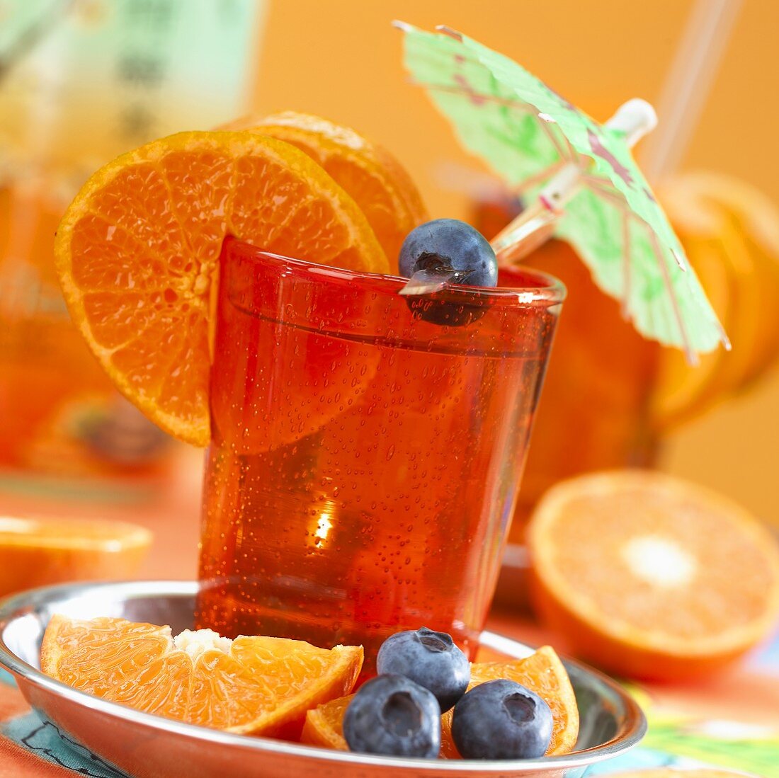 Clementine juice with cocktail umbrellas and garnished with blue berries