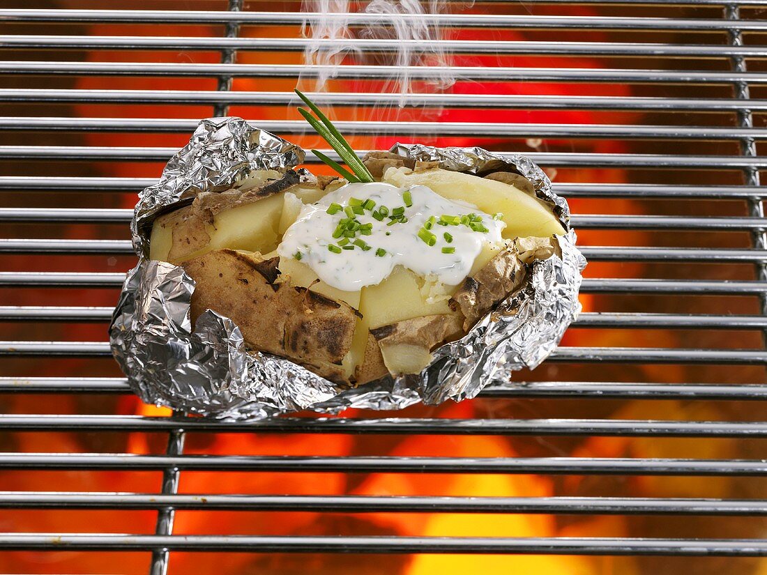 Baked potatoes in aluminum foil on the grill