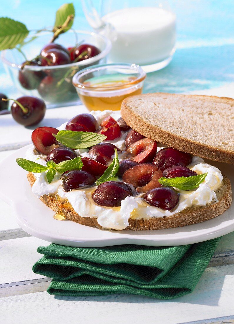 Open faced sandwich with cream cheese, honey and cherries