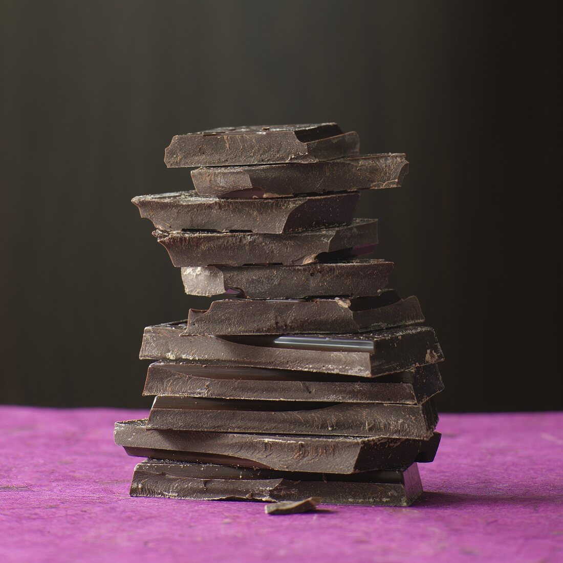 Pieces of chocolate stacked on a pink colored surface