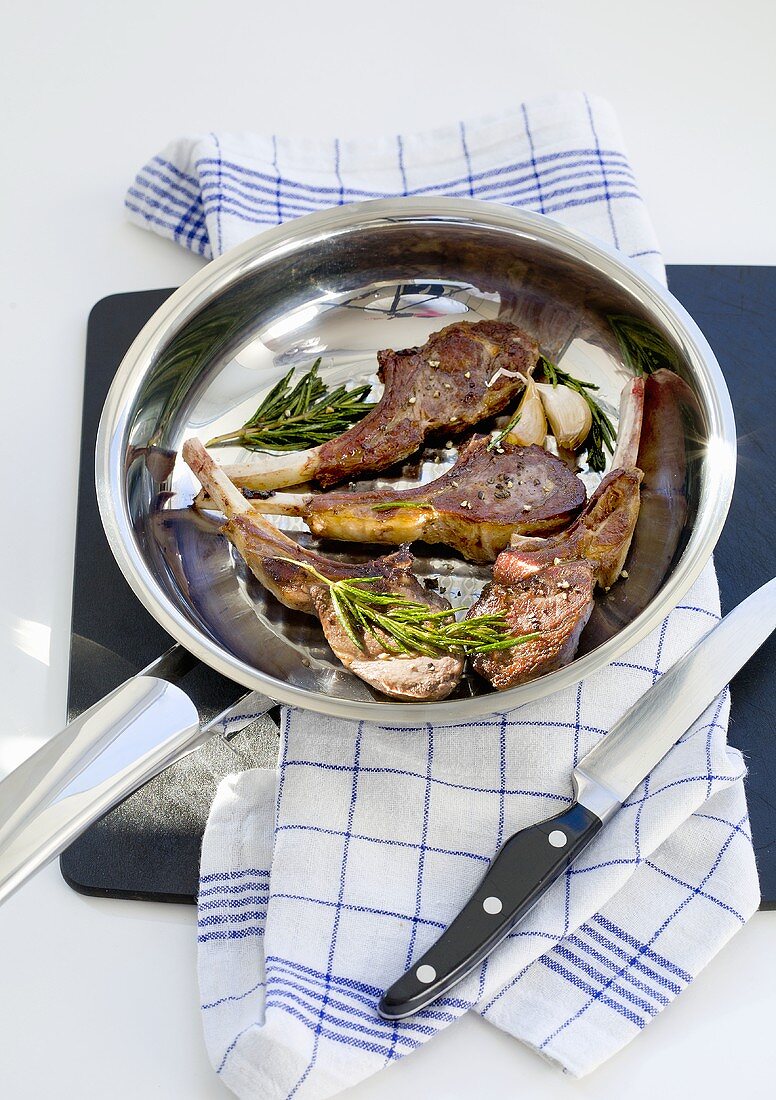 Lamb cutlets with rosemary and garlic in a pan