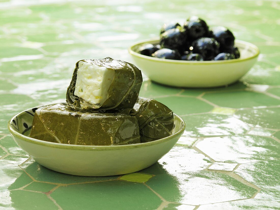 Stuffed grape leaves and olives in dishes