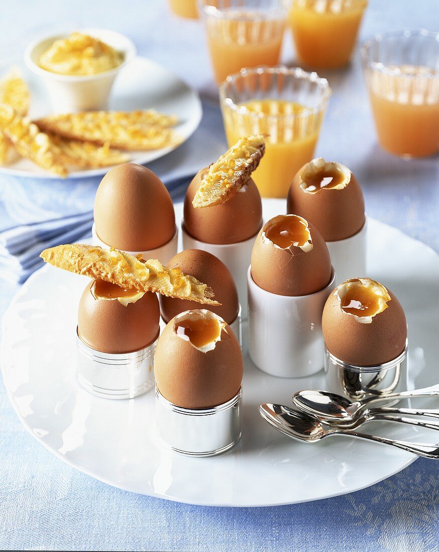 Weiche Eier mit Käsebrötchen; dazu Orangensaft