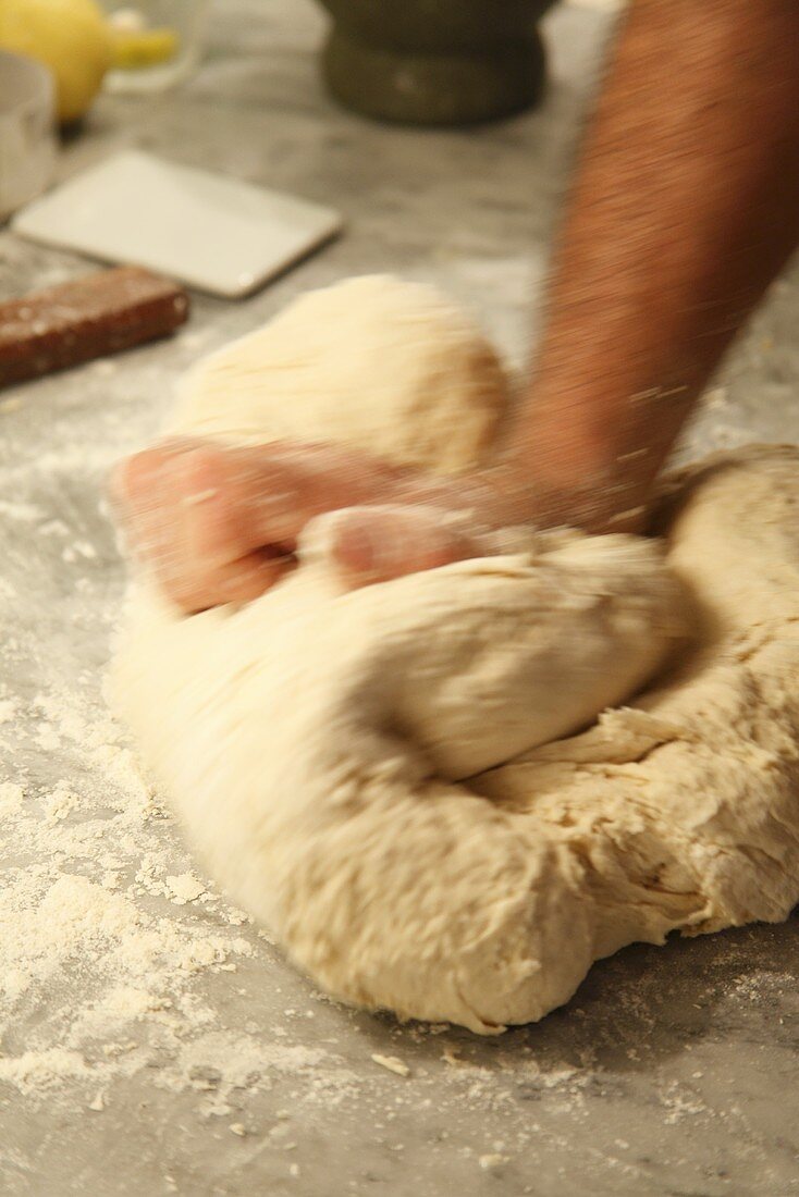 A man's hands kneading bread dough