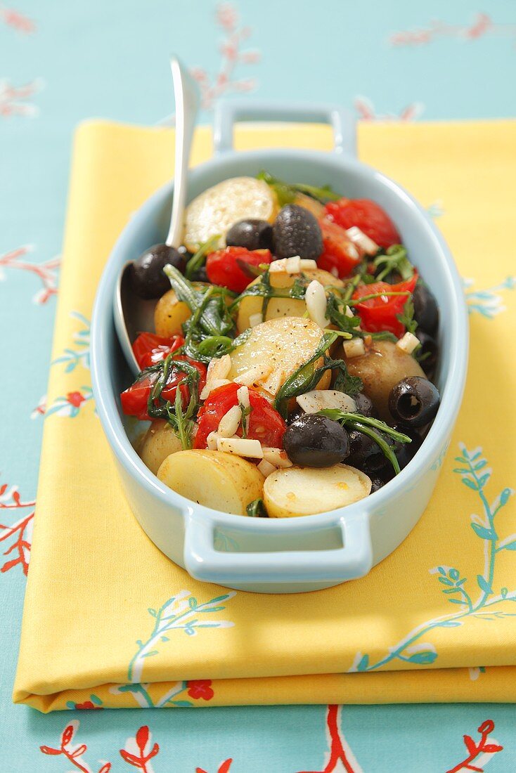 Potato casserole with olives, cherry tomatoes and rocket