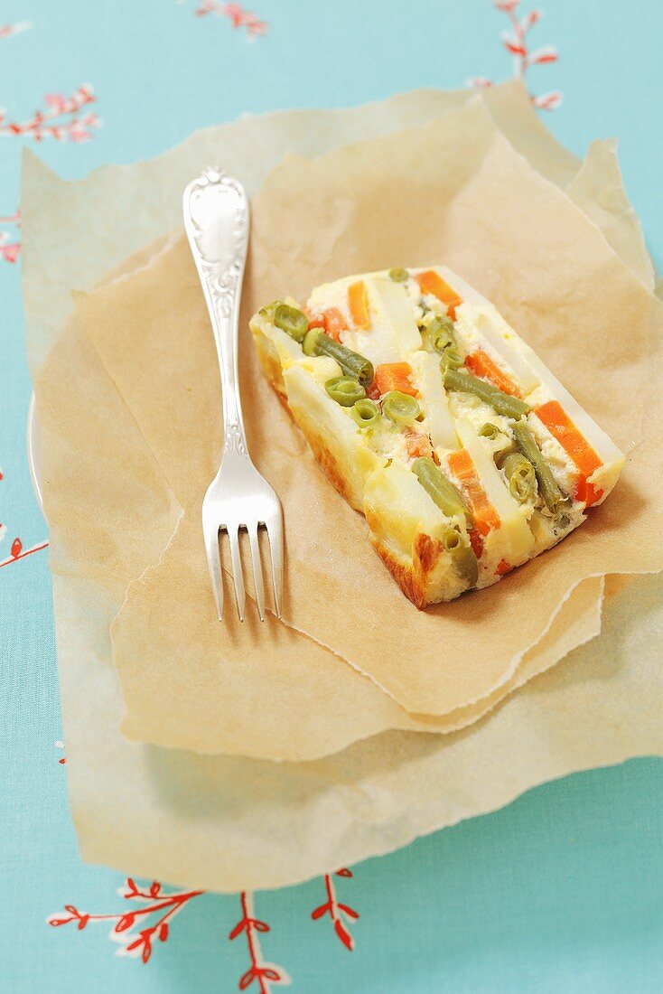 A slice of vegetable terrine with potatoes, carrots and green beans