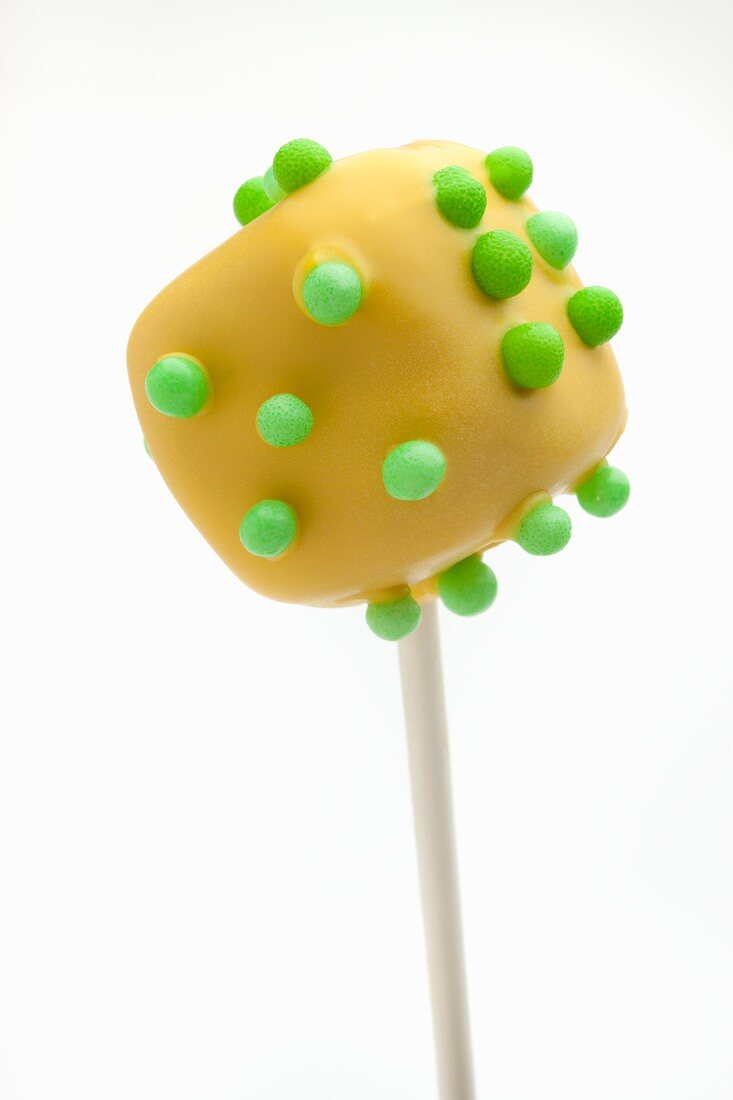 Gelber würfelförmiger Cake Pop mit grünen Zuckerperlen
