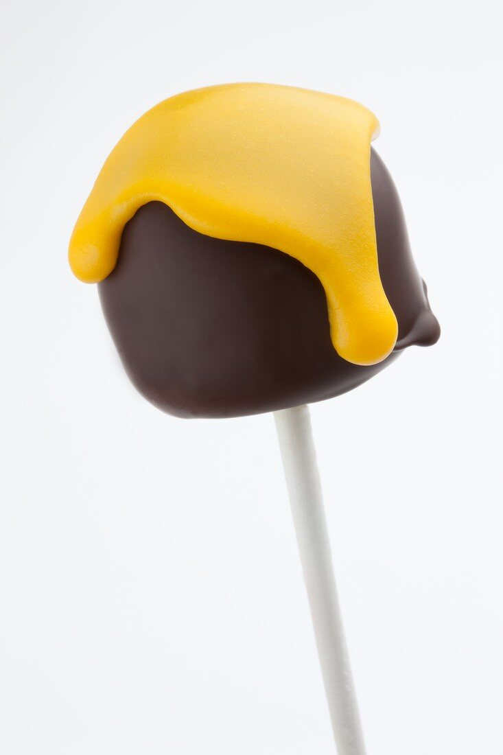 A cake pop shaped like a mini chocolate marshmallow with yellow icing