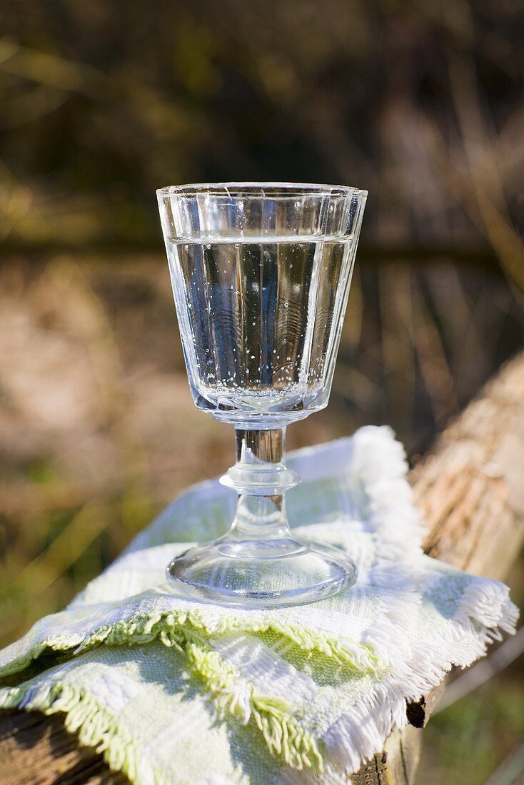 Ein Glas Wasser auf Holzzaun im Freien stehend