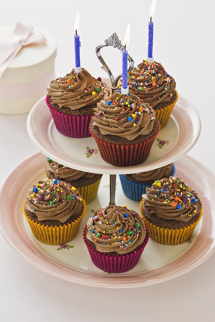 Chocolate cupcakes with candles on a cake stand