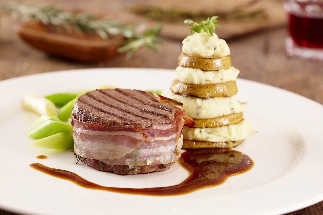Beef medallions wrapped in bacon with a pear and mashed potato tower