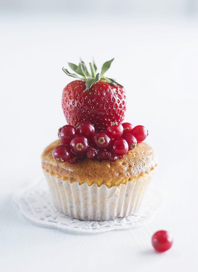 A muffin topped with redcurrants and strawberries
